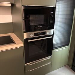 Grün gestalteter Küchenbereich mit Ofen und Mikrowelle, die eine zeitgemäße und funktionale Atmosphäre schaffen