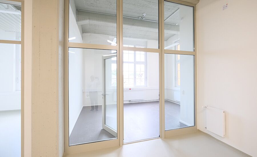 Ein modernes Atelier-Büro mit einer großen Glastür und Fenstern, die viel Tageslicht in den Raum lassen