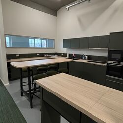 Küche mit natürlichen Holzoberflächen, modernen schwarzen Hockern und einem klaren, minimalistischen Look