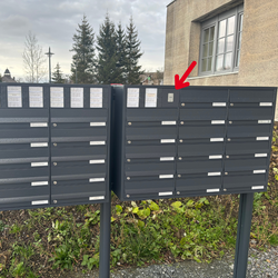 Bild von zwei schwarzen Briefkästen, mit einem roten Pfeil, der auf einen Briefkasten zeigt
